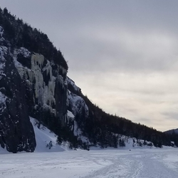 Avalanche lake in the winter, the surface and the cliffs clad in ice.